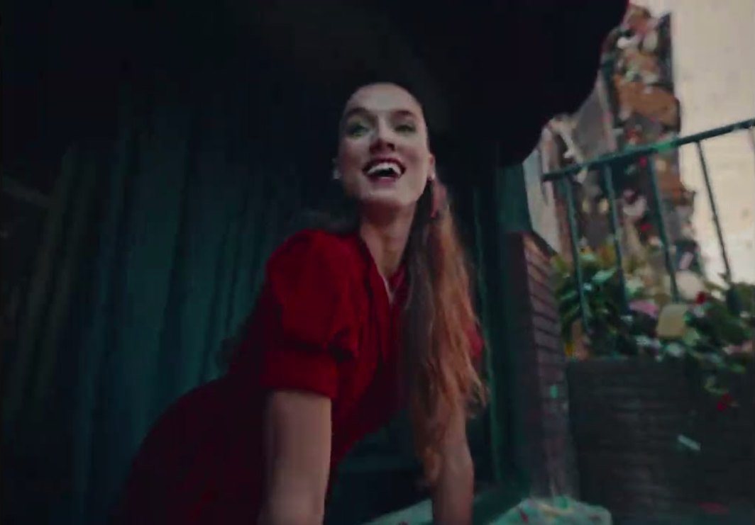 Fotograma del spot: una chica con vestido rojo se asoma sonriendo a un balcón